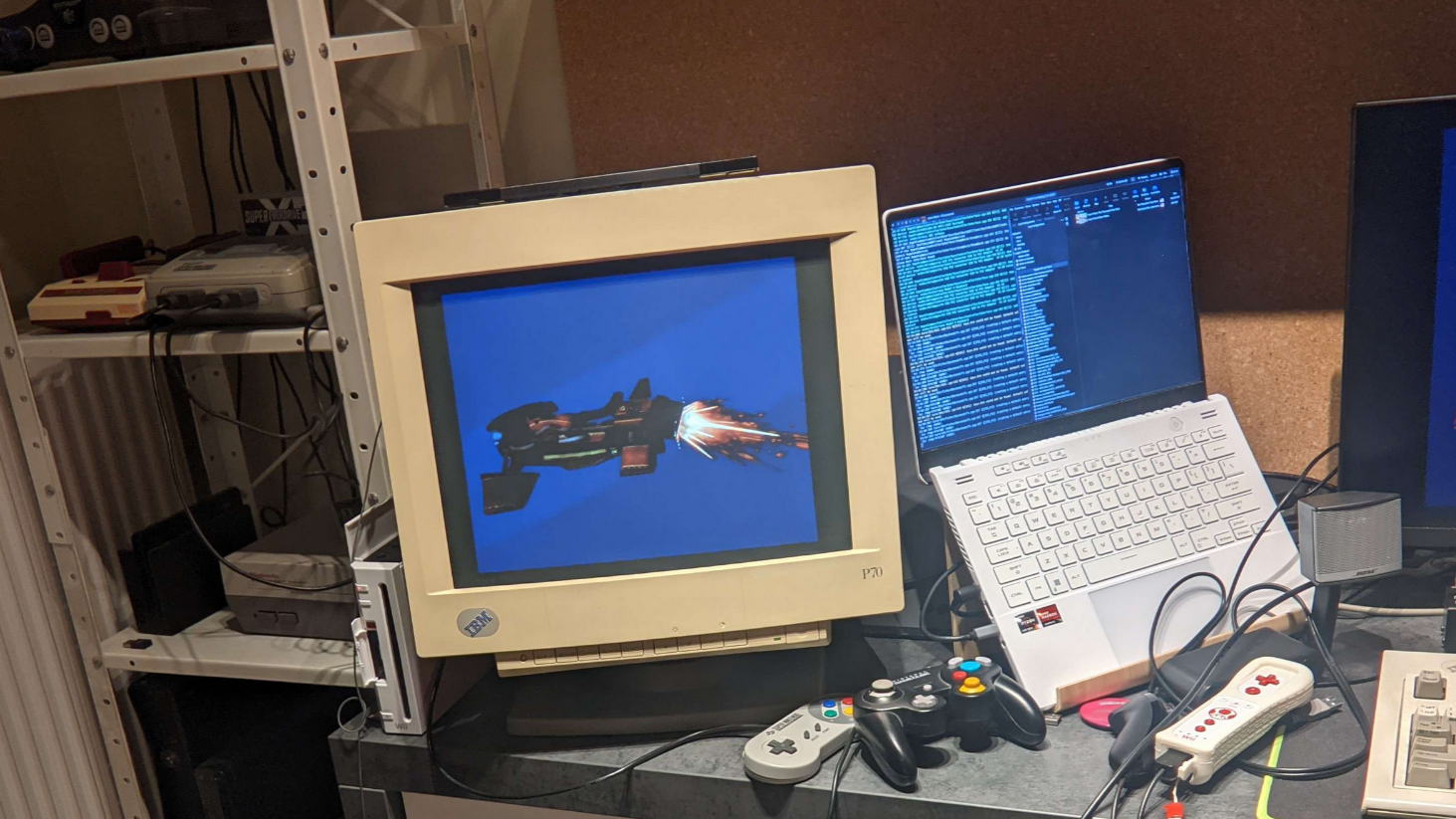 A picture of a messy table with a Wiimote and GameCube controller, with a CRT hooked up to an offscreen GameCube showing a vehicle with a fire effect behind it